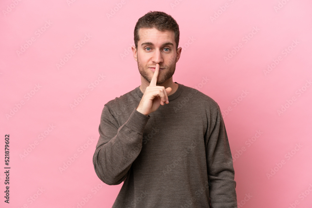 Young caucasian man isolated on pink background showing a sign of silence gesture putting finger in mouth Young caucasian man isolated on pink background showing a sign of silence gesture putting finger in mouth