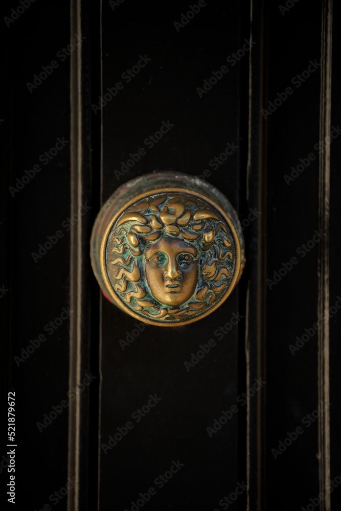 Vertical shot of an old door knob with female head design on Georgian black front door Vertical shot of an old door knob with female head design on Georgian black front door