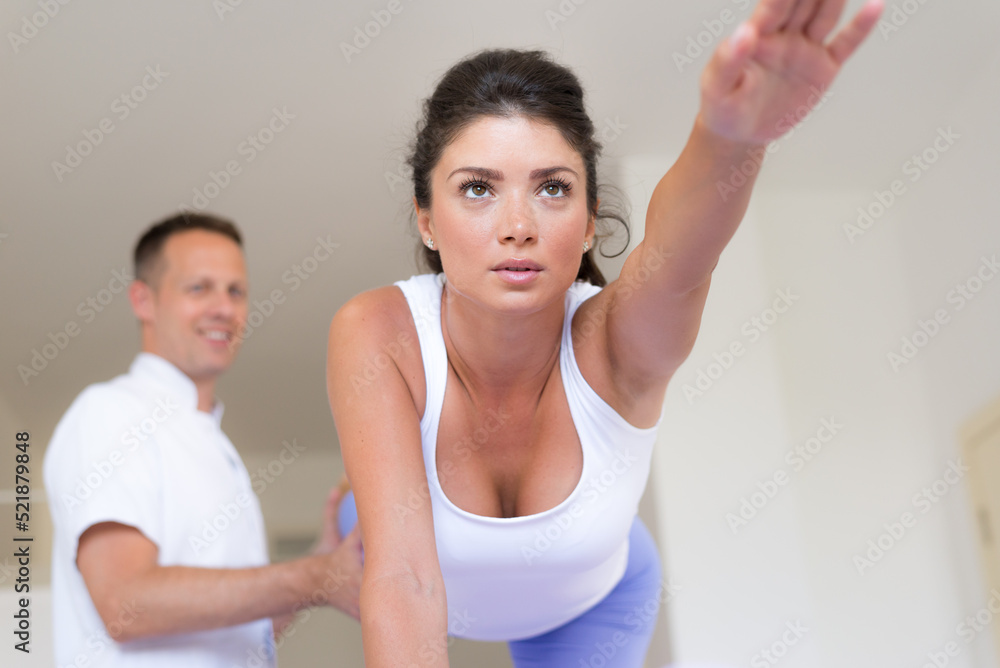 Young woman exercising on physiotherapy with help of physiotherapist during rehabilitation Young woman exercising on physiotherapy with help of physiotherapist during rehabilitation