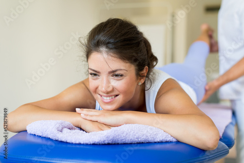 Young woman exercising on physiotherapy with help of physiotherapist during rehabilitation