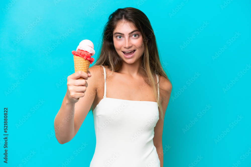 Young woman in swimsuit holding an ice cream isolated on blue background with happy expression Young woman in swimsuit holding an ice cream isolated on blue background with happy expression