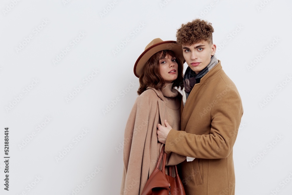 loving couple, a man and a woman are standing on a white background in an autumn coat, a woman has a hat on her head and she is holding a brown bag, and a man is holding her by the edge of the coat loving couple, a man and a woman are standing on a white background in an autumn coat, a woman has a hat on her head and she is holding a brown bag, and a man is holding her by the edge of the coat