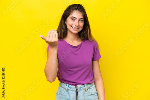 Young caucasian woman isolated on yellow background inviting to come with hand. Happy that you came