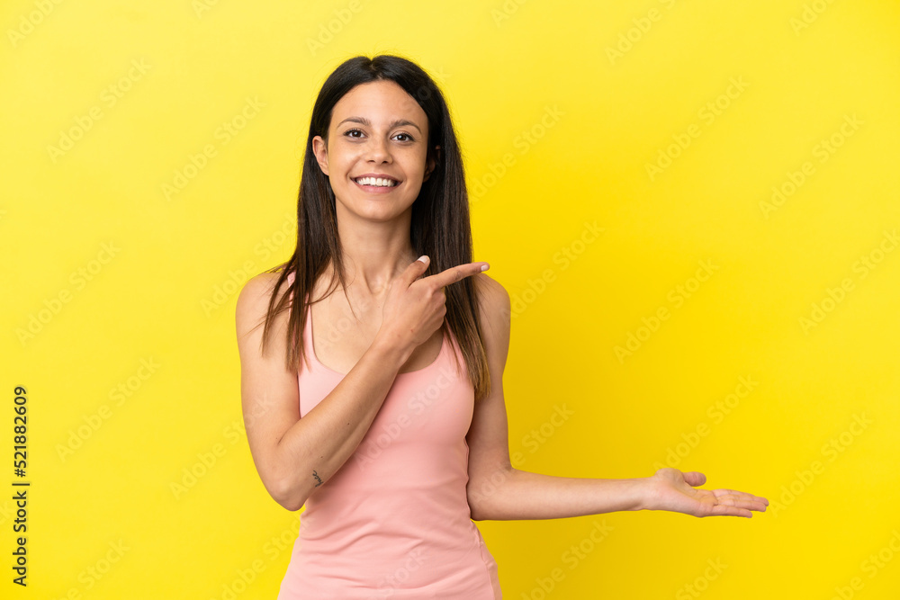 Young caucasian woman isolated on yellow background holding copyspace imaginary on the palm to insert an ad Young caucasian woman isolated on yellow background holding copyspace imaginary on the palm to insert an ad