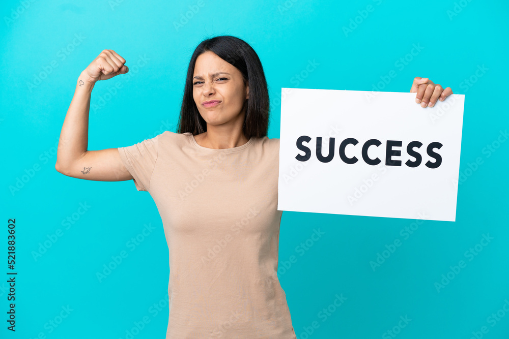 Young woman over isolated background holding a placard with text SUCCESS and doing strong gesture Young woman over isolated background holding a placard with text SUCCESS and doing strong gesture