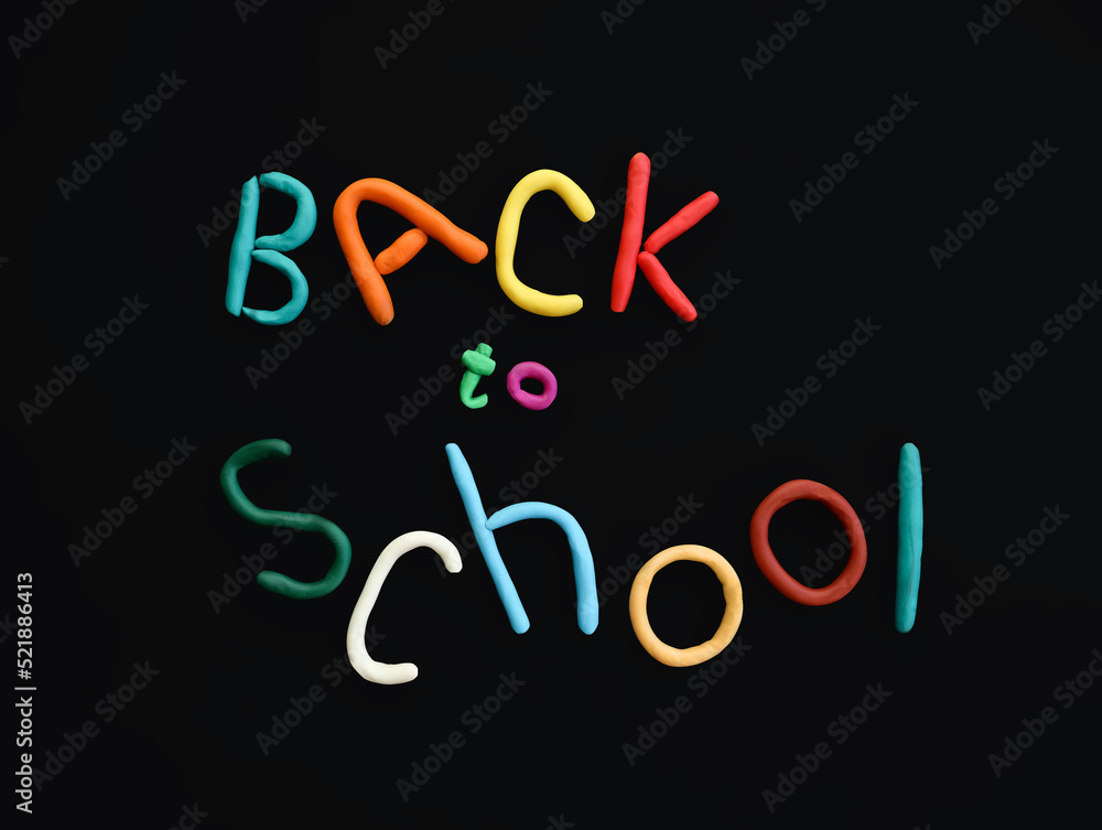 letters made of multi-colored plasticine back to school in wry funny style on black background