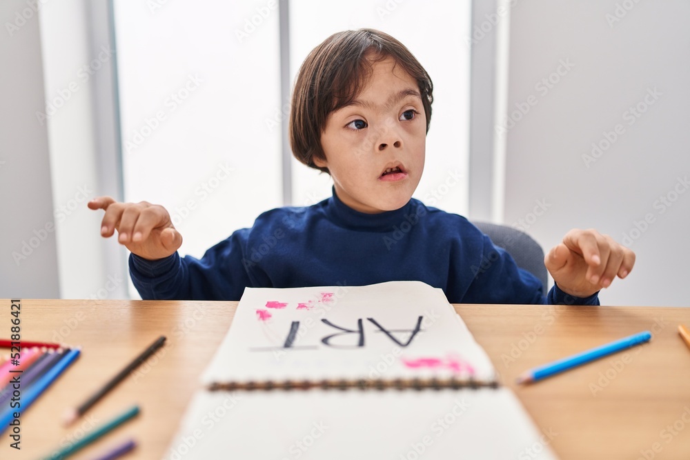 Down syndrome kid drawing on notebook at school Down syndrome kid drawing on notebook at school