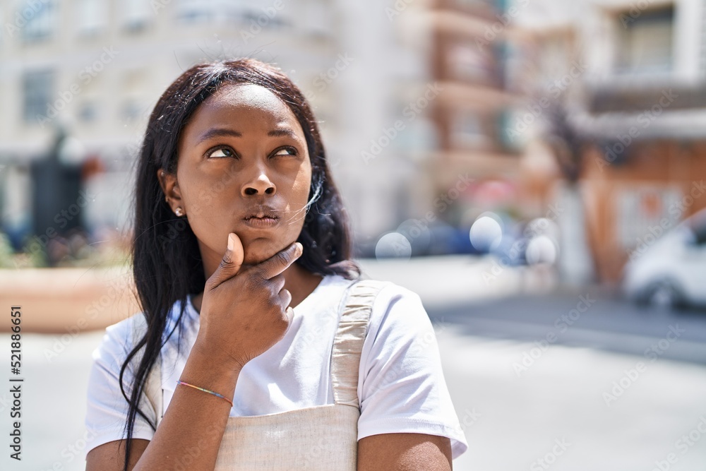 Young african american woman standing with doubt expression at street