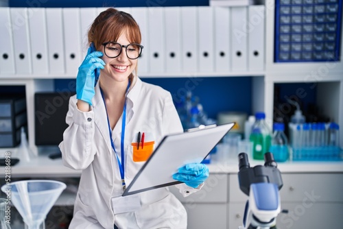 Young woman scientist smiling confident talking on the smartphone at laboratory