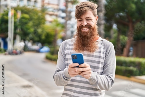 Young redhead man smiling confident using smartphone at street