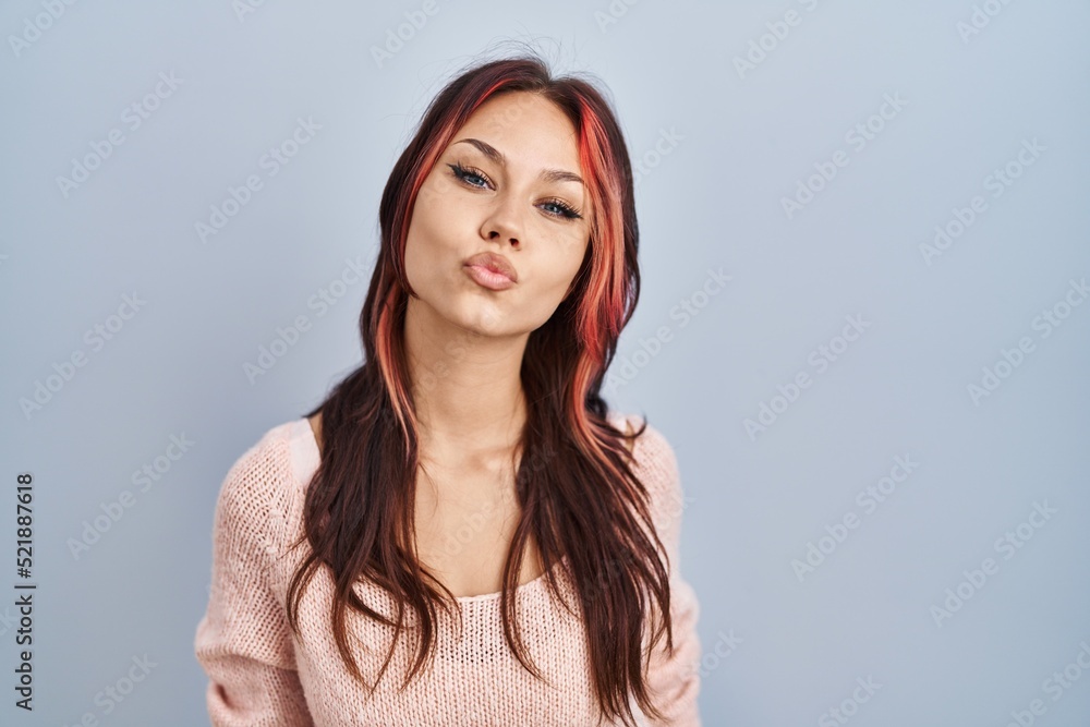 Young caucasian woman wearing pink sweater over isolated background looking at the camera blowing a kiss on air being lovely and sexy. love expression. Young caucasian woman wearing pink sweater over isolated background looking at the camera blowing a kiss on air being lovely and sexy. love expression.