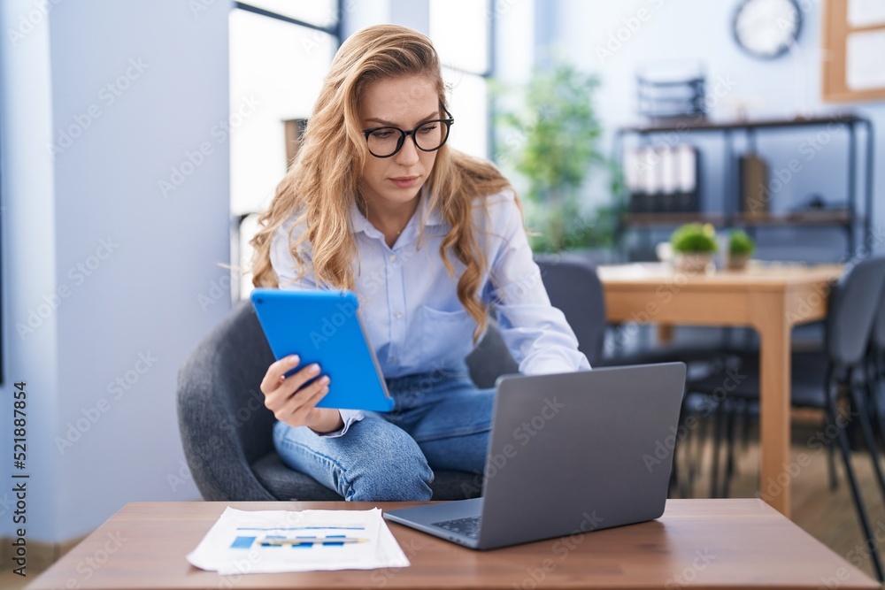 Young blonde woman business worker using laptop and touchpad at office Young blonde woman business worker using laptop and touchpad at office