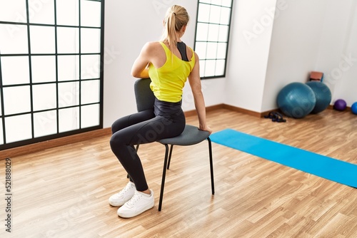 Young blonde girl on back view training at sport center.