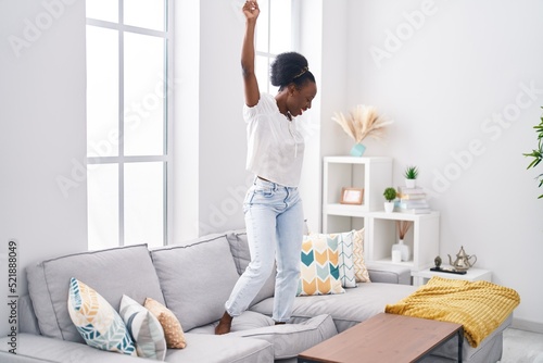 African american woman smiling confident dancing on sofa at home