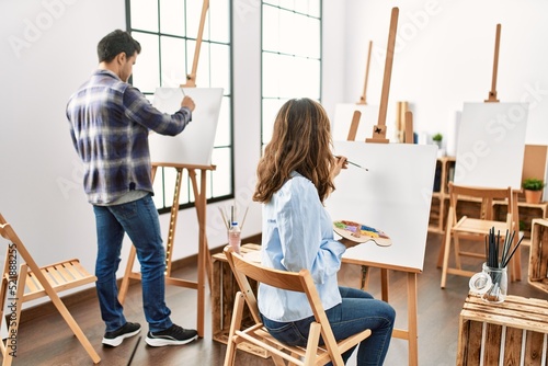 Two hispanic students smiling happy painting at art school.