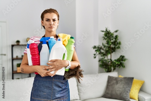 Young woman holding cleaning products at home