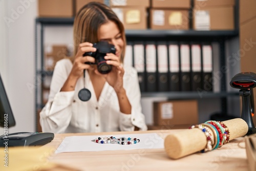 Young hispanic woman ecommerce business worker make photo to bracelet at office
