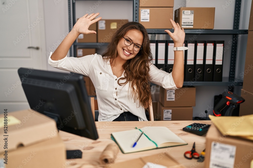 Young hispanic woman working at small business ecommerce showing and pointing up with fingers number ten while smiling confident and happy. Young hispanic woman working at small business ecommerce showing and pointing up with fingers number ten while smiling confident and happy.