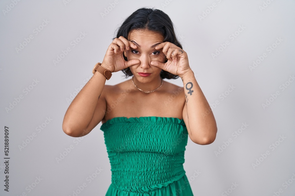 Young hispanic woman standing over isolated background trying to open eyes with fingers, sleepy and tired for morning fatigue Young hispanic woman standing over isolated background trying to open eyes with fingers, sleepy and tired for morning fatigue