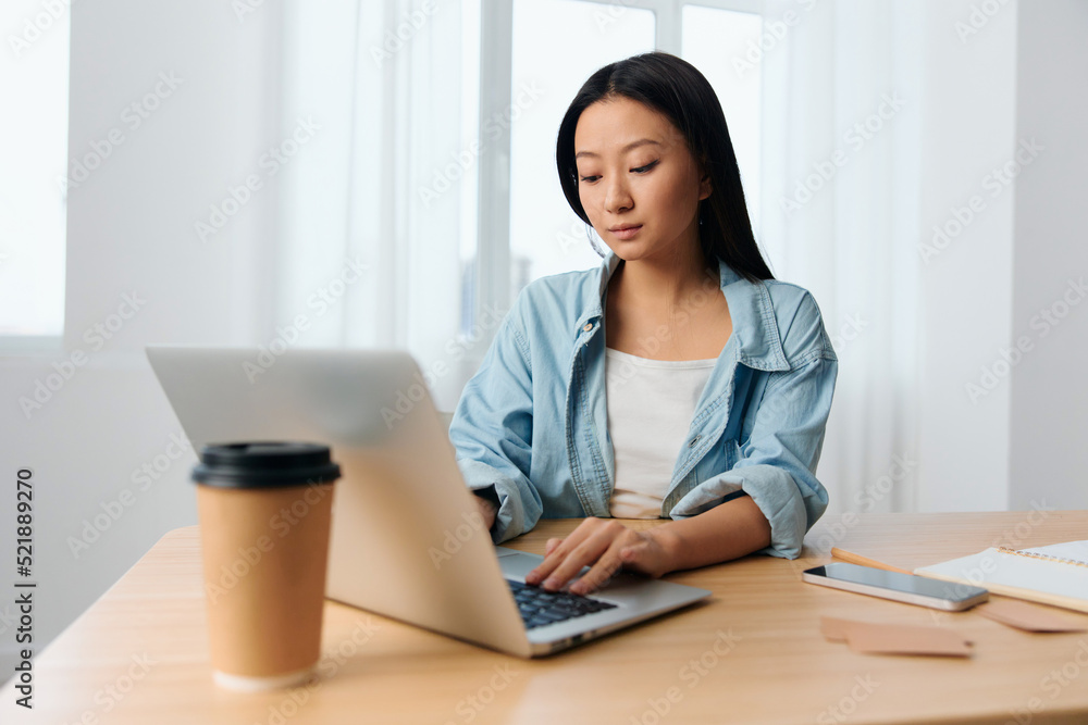 Focused serious young Asian cute female businesswoman type tax report on laptop in light office interior. Employee freelancer work at home. Lady corporation leader concept. Copy space Banner Offer