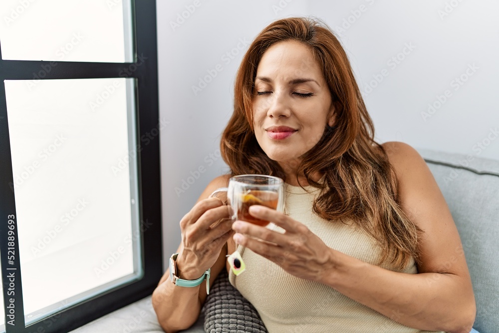 Young latin woman drinking tea sitting on sofa at home Young latin woman drinking tea sitting on sofa at home