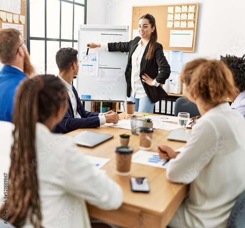 Group of business workers listening hispanic boss woman conference at the office.