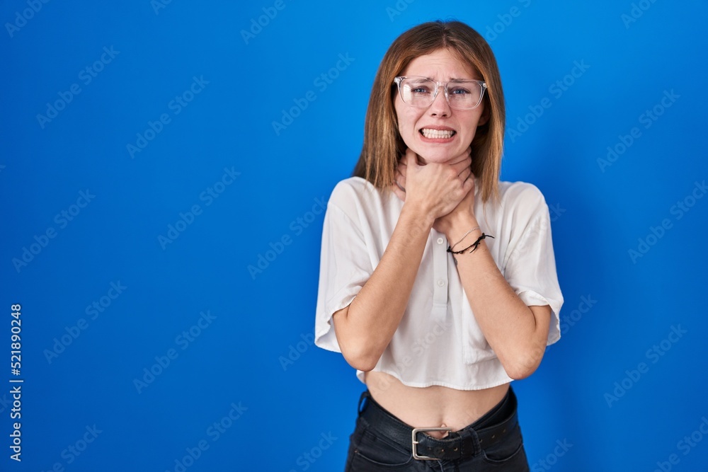 Beautiful woman standing over blue background shouting and suffocate because painful strangle. health problem. asphyxiate and suicide concept. Beautiful woman standing over blue background shouting and suffocate because painful strangle. health problem. asphyxiate and suicide concept.