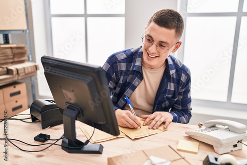 Young hispanic man ecommerce business worker writing on package at office