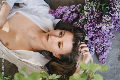 a sexy topless blonde in a white shirt on the floor with lilac flowers photo