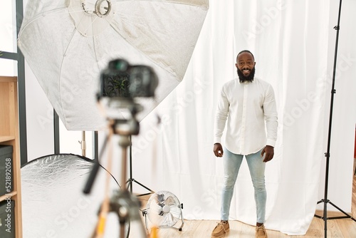 African american man posing as model at photography studio looking positive and happy standing and smiling with a confident smile showing teeth photo