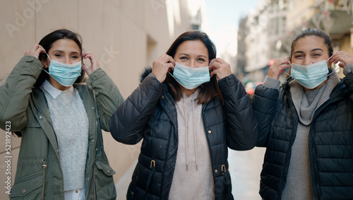 Mother and daugthers wearing medical mask standing together at street