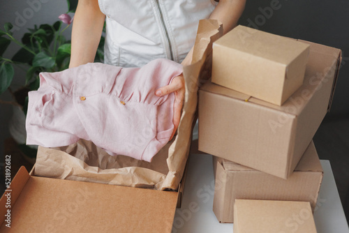 female entrepreneur sells children's clothes online and packs them in boxes to be sent to a delivery service. small business selling goods on the Internet on the marketplace. handmade or factory-made