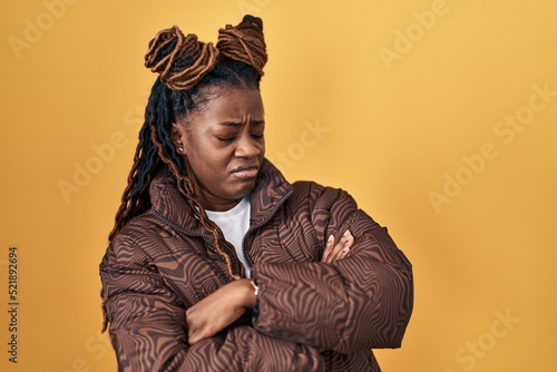 African woman with braided hair standing over yellow background looking to the side with arms crossed convinced and confident © Krakenimages.com