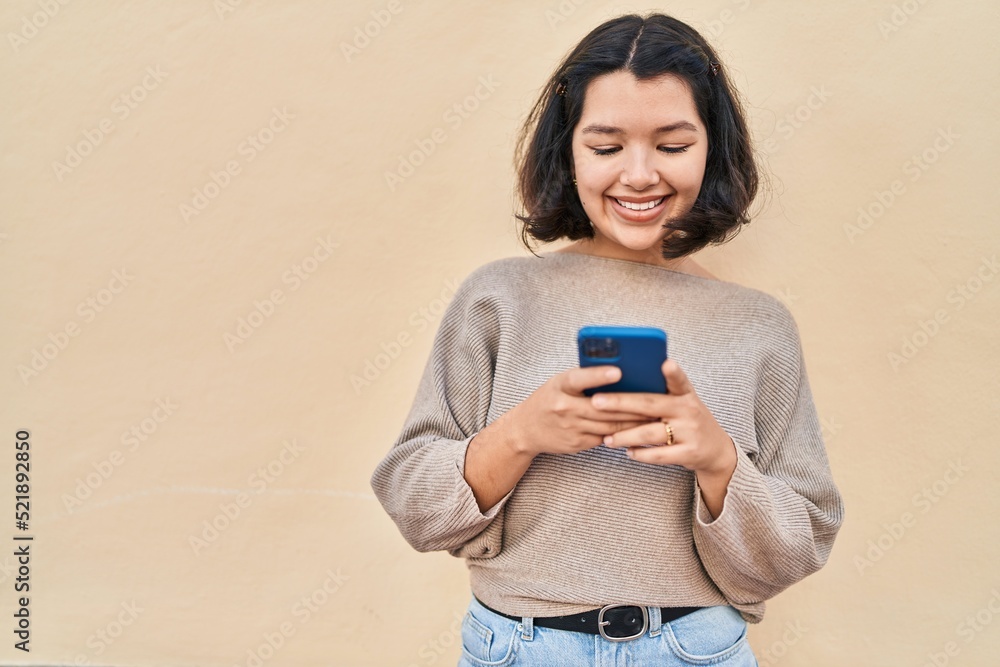 Young woman smiling confident using smartphone over yellow background Young woman smiling confident using smartphone over yellow background