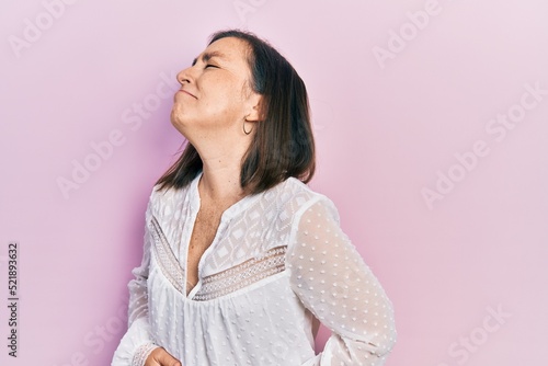 Middle age hispanic woman wearing casual clothes with hand on stomach because nausea, painful disease feeling unwell. ache concept.