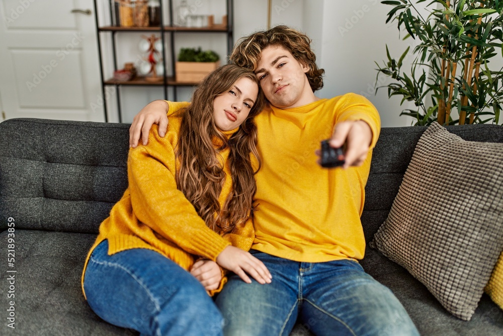 Young caucasian couple watching movie hugging each other at home Young caucasian couple watching movie hugging each other at home