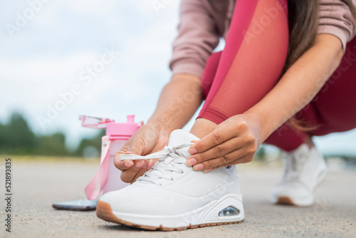 girl athlete straightens shoelaces on sneakers with a bottle of water