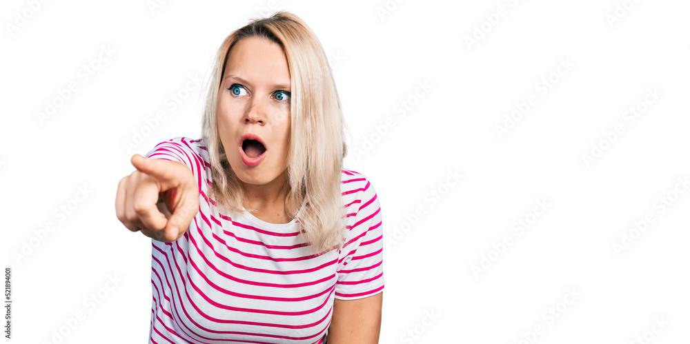 Young caucasian woman wearing casual clothes pointing with finger surprised ahead, open mouth amazed expression, something on the front Young caucasian woman wearing casual clothes pointing with finger surprised ahead, open mouth amazed expression, something on the front