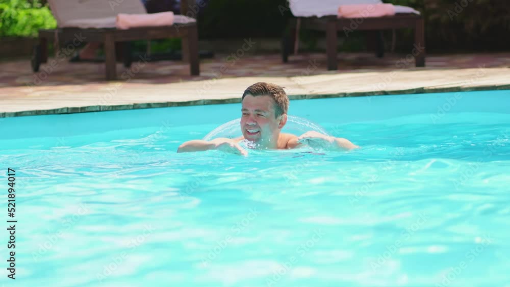 a man swims in a pool with an inflatable circle. a man swims in a pool with an inflatable circle.