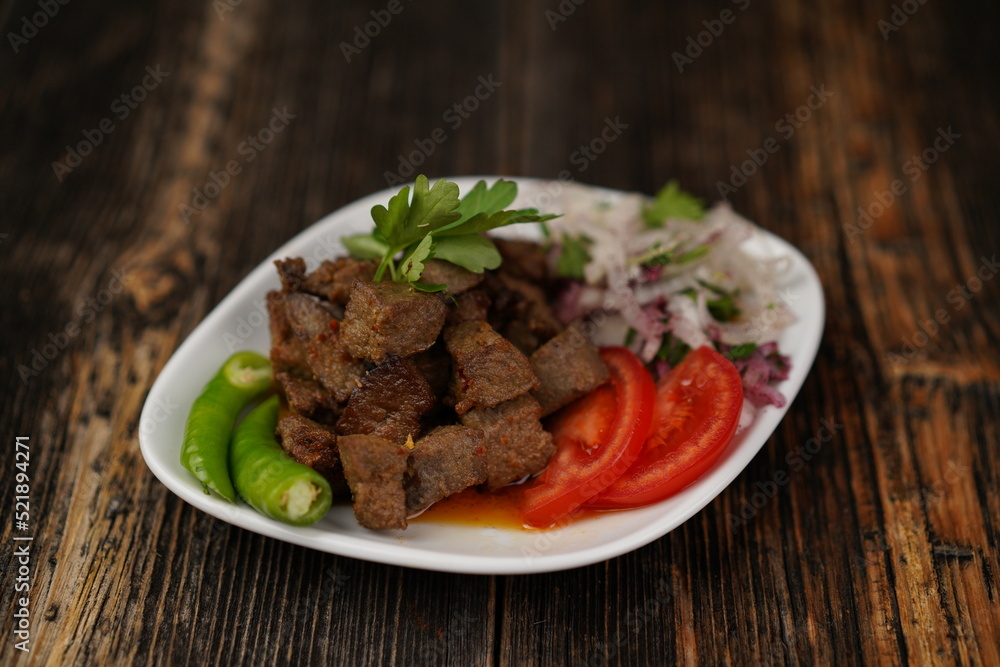 Traditional Turkish food ciger with onion, tomatoes and green pepper. Ciger made with beef liver. Beef liver marinated with milk and cooked in oil. Traditional street food in Turkey.