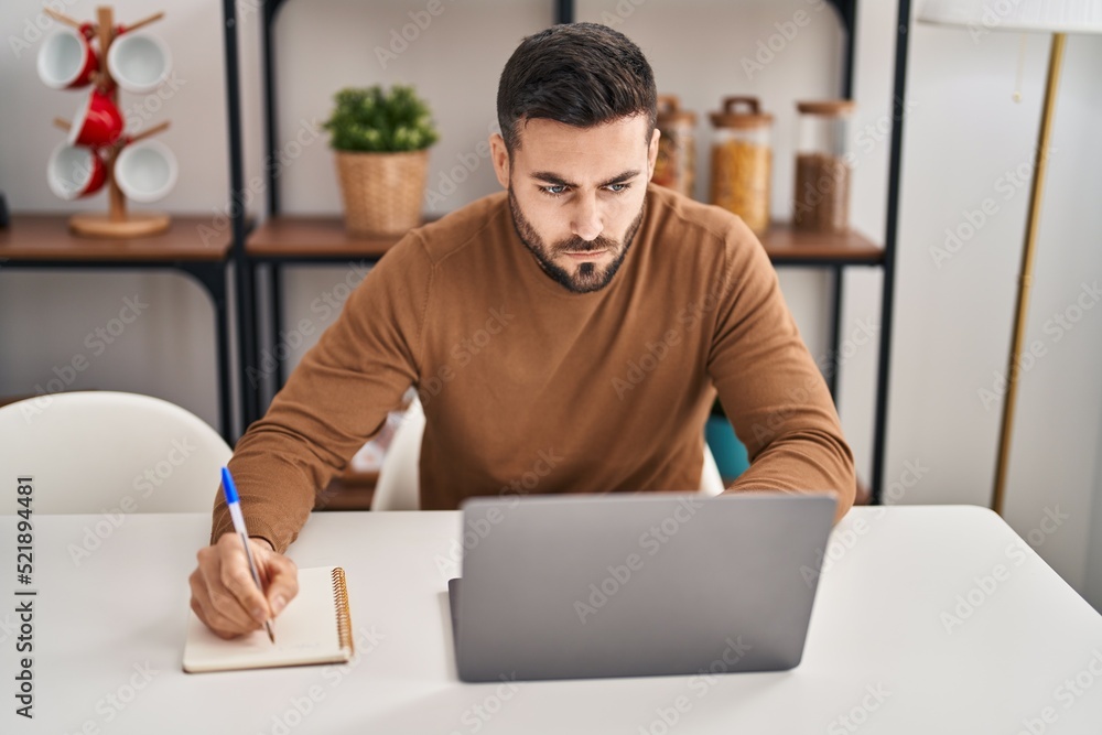 Young hispanic man using laptop sitting on table at home Young hispanic man using laptop sitting on table at home