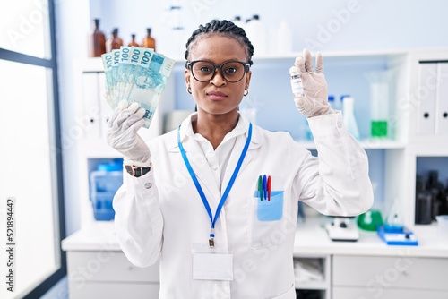 African woman with braids working at scientist laboratory holding money skeptic and nervous  frowning upset because of problem. negative person.
