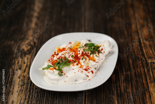Traditional appetizer (meze) Atom made with chili peppers and yogurt in a traditional pot on wooden background. Healthy, vegetarian, hot chili peppers appetizer. Turkish appetizer atom with yogurt