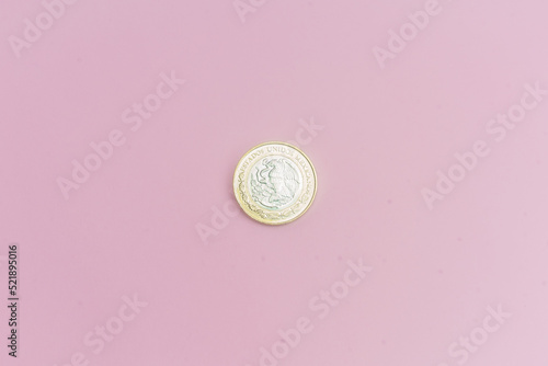 Moneda de 10 pesos mexicanos sobre fondo rosa.