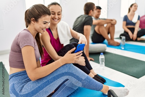 Group of young hispanic people smiling happy relaxing and using smartphone at sport center.