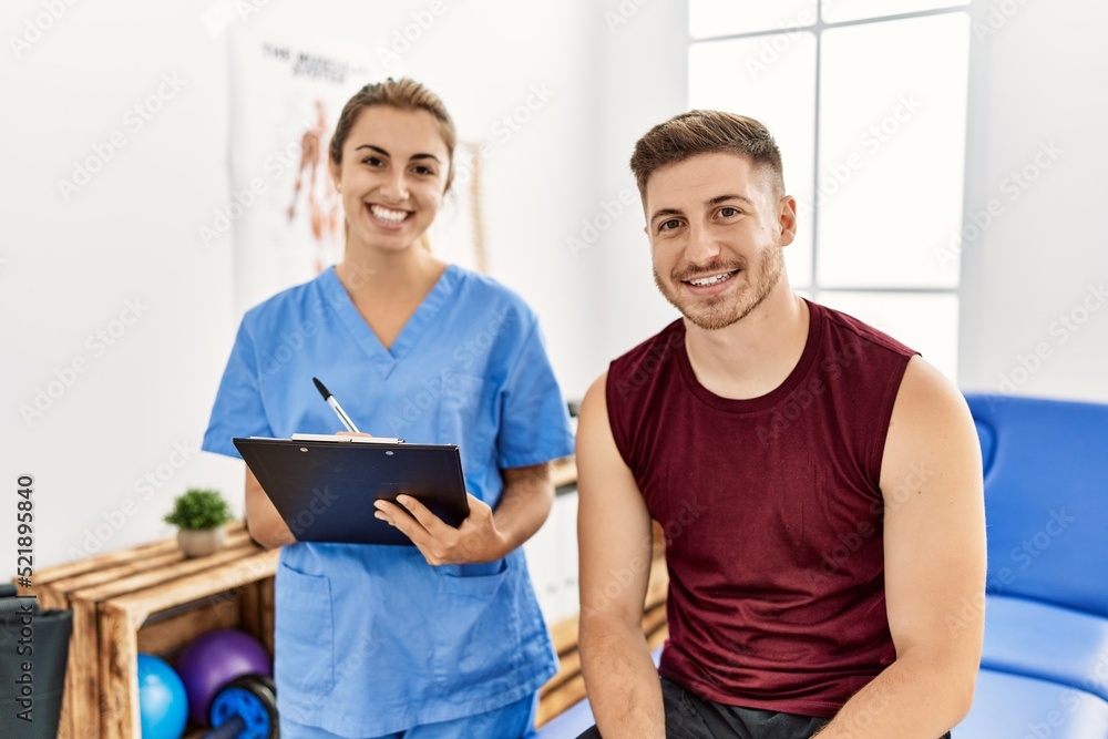 Obraz premium Young hispanic physioterapist woman explain diagnosis to patient man at the clinic.