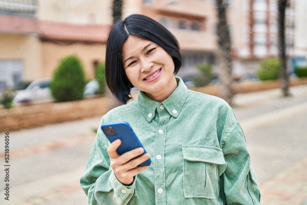 Young chinese woman smiling confident using smartphone at street Young chinese woman smiling confident using smartphone at street