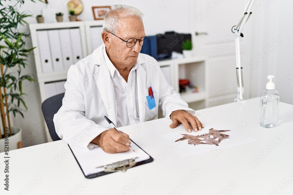 Senior man wearing doctor uniform doing rorscharch test at clinic