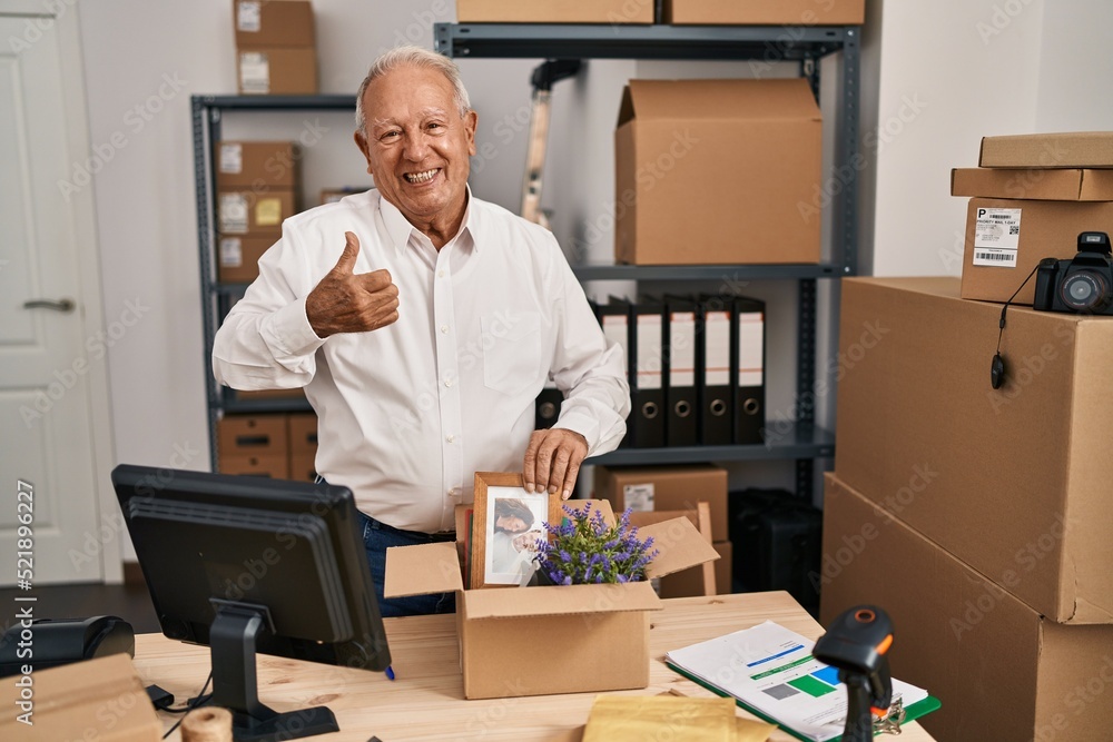 Senior man with grey hair working at small business ecommerce smiling happy and positive, thumb up doing excellent and approval sign Senior man with grey hair working at small business ecommerce smiling happy and positive, thumb up doing excellent and approval sign