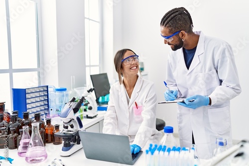 Man and woman scientist partners smiling confident working at laboratory